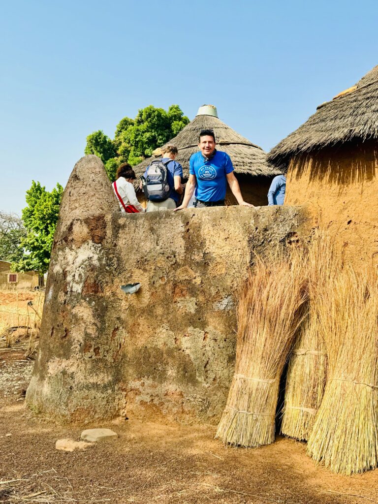 a solo male traveler peeking out from local African village during his cultural discovery tour in West Africa