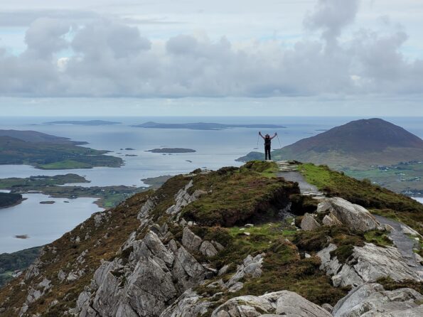 hiker ascending top of Connemara, one of three isolated rocky outcrops of the Aran Islands, during group hiking adventure in Ireland, Europe
