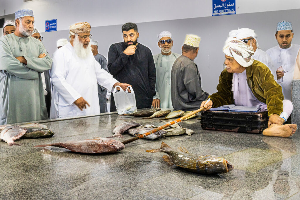 local sellers haggling prices at marketplace with local villagers over fish in Oman in the Middle East
