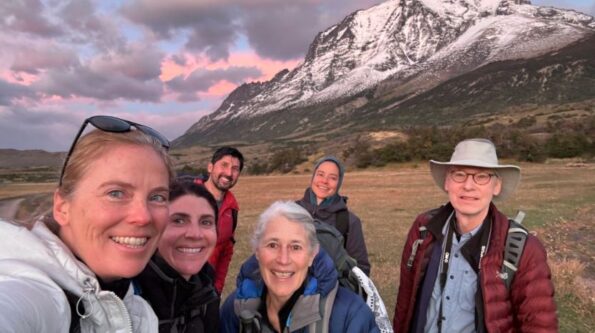 Group of hikers with Diane facing Patagonia breathtaking scenery during a sunset on a hiking trail