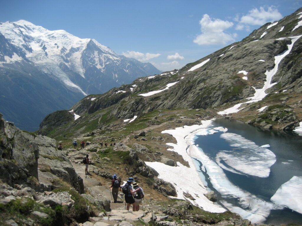two travelers hiking trails near glaciers in Tour du Mont Blanc hiking circuit in the summer