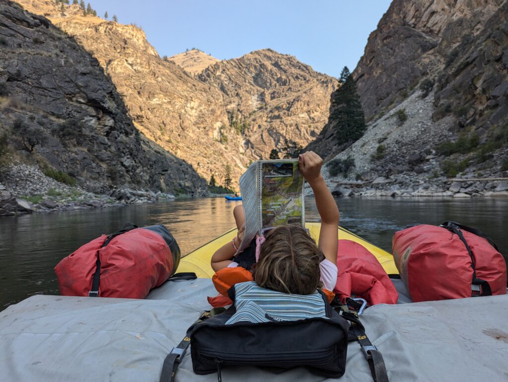 reading map of Idaho Middle Fork while on floatable oar boat 