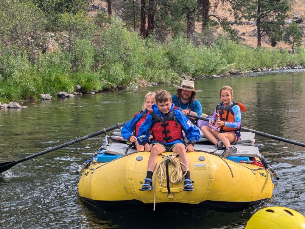 on the oar boat with kids and our rafting guides going downstream in Idaho Middle Fork in August