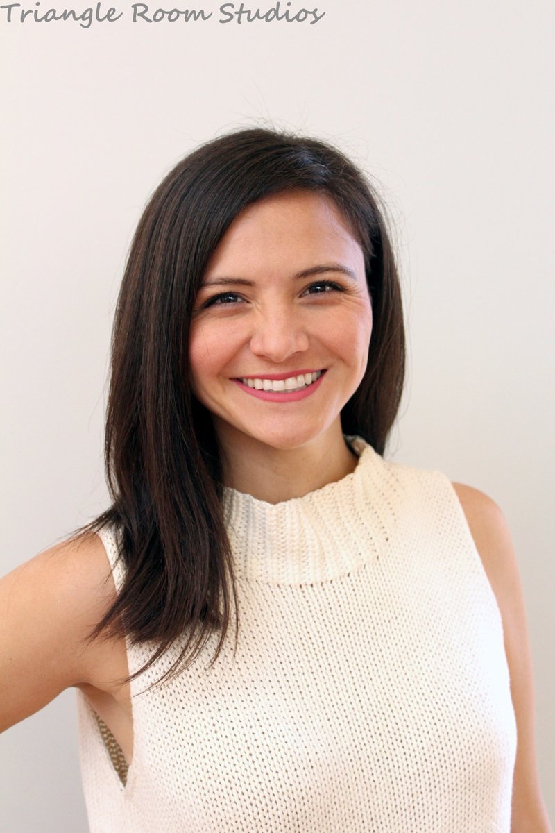 A woman with straight dark hair and a sleeveless cream knit top smiles at the camera against a plain light background. "Triangle Room Studios" text appears at the top.