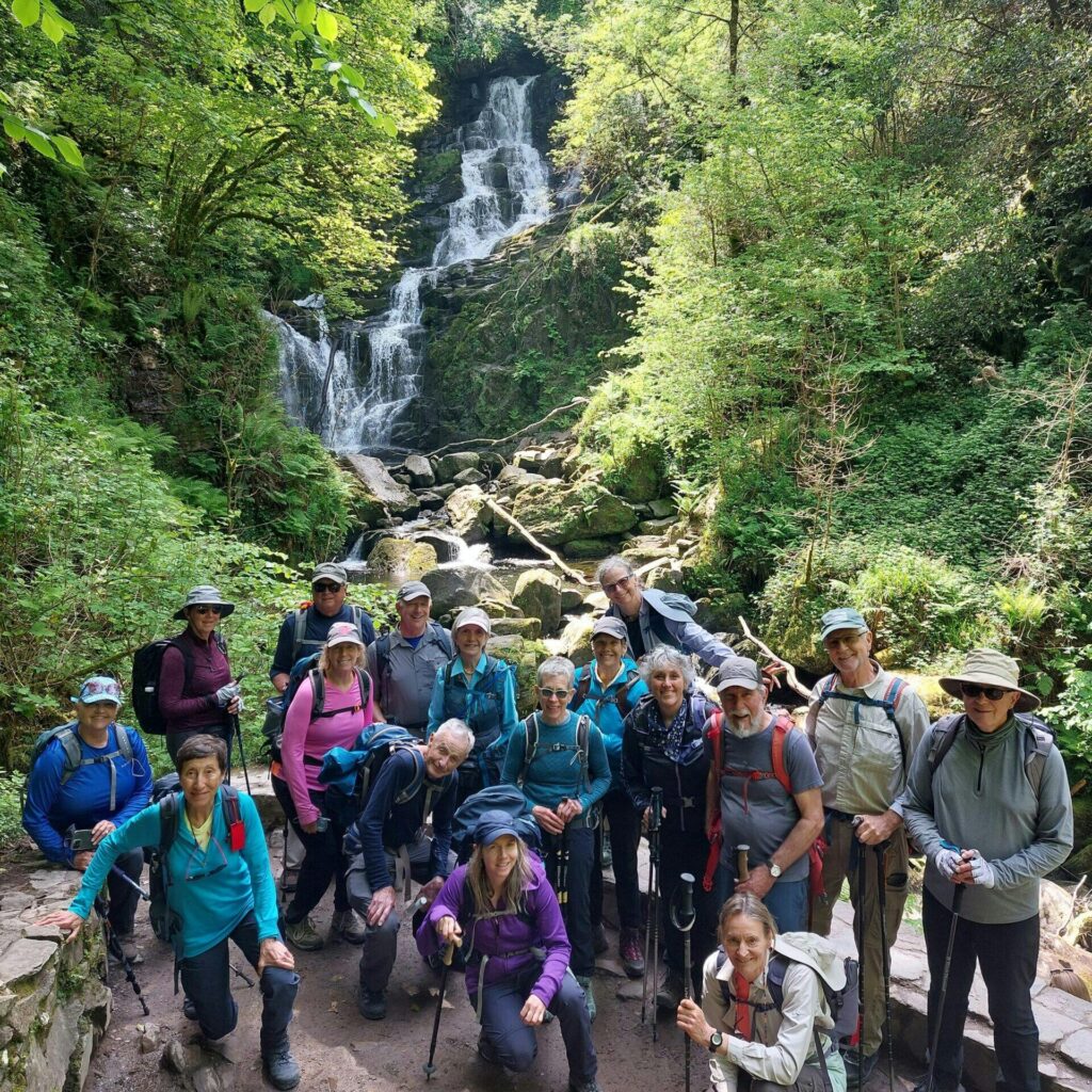 hiking in big group to Torc Waterfall near mountain in Ireland, Europe