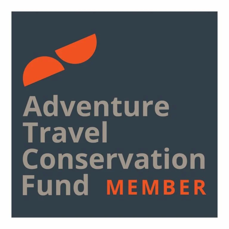 Square logo featuring two orange semicircles above the words "Adventure Travel Conservation Fund MEMBER" in gray and orange text, highlighting a commitment to conservation, set against a dark background.